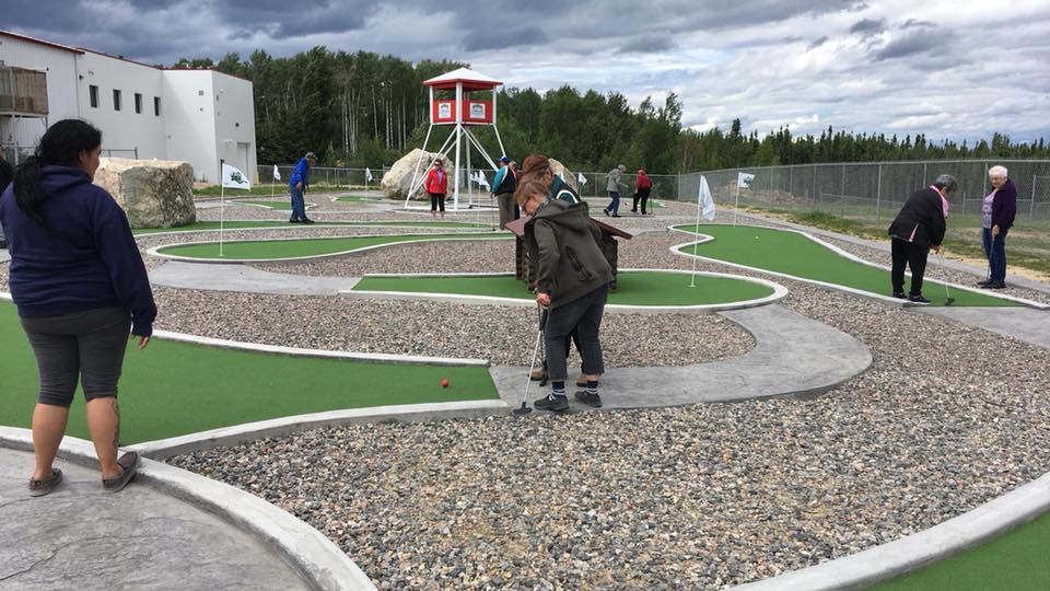 A picture of some elders playing mini golf and enjoying their time outside.