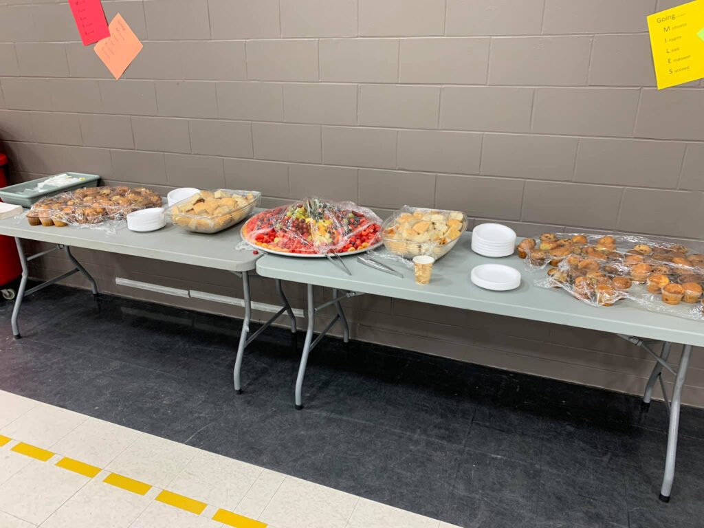 a buffet of food displayed on fold out tables in the gym/hall.